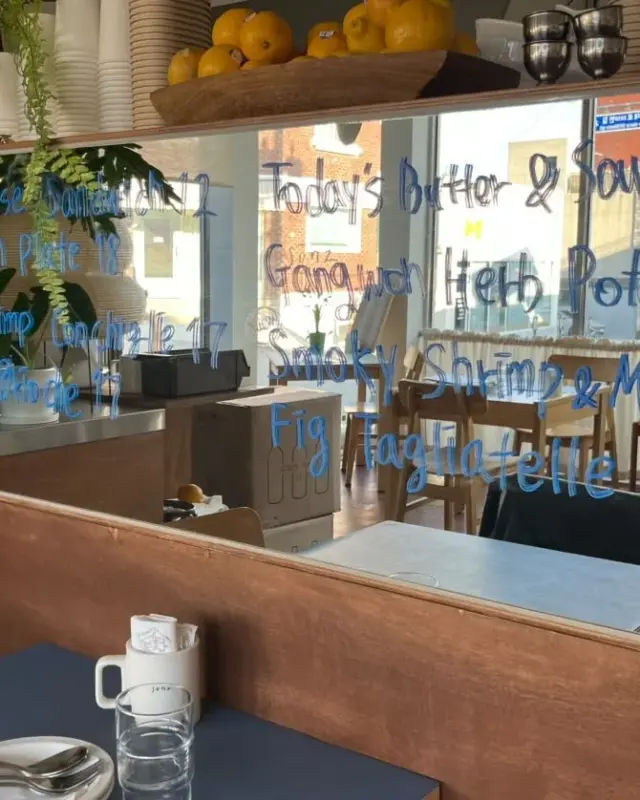 Handwritten seasonal dishes on the mirror beside a table at Sonz in Saemaeul